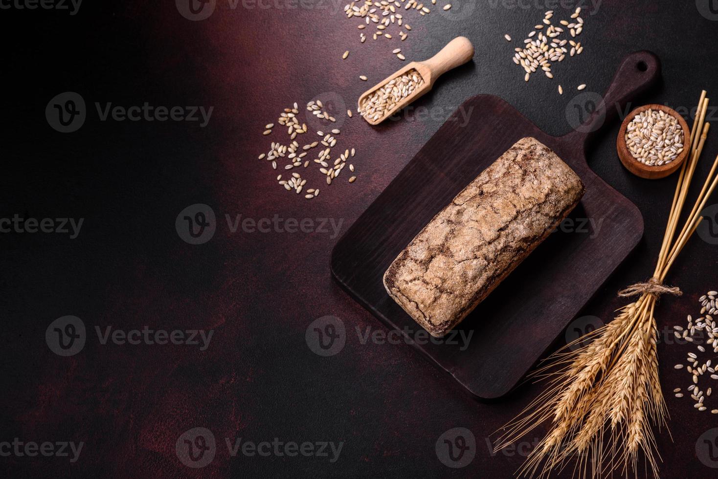 A loaf of brown bread with grains of cereals on a wooden cutting board photo