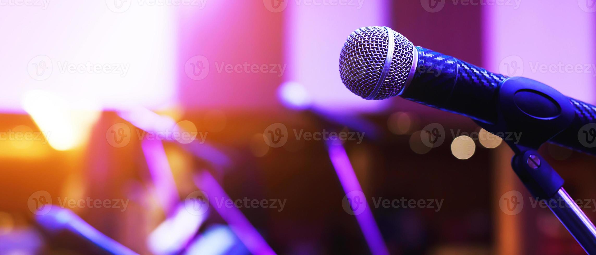 primer plano del micrófono en la iluminación del escenario en la sala de conciertos o sala de conferencias. copie la pancarta del espacio. enfoque suave. foto