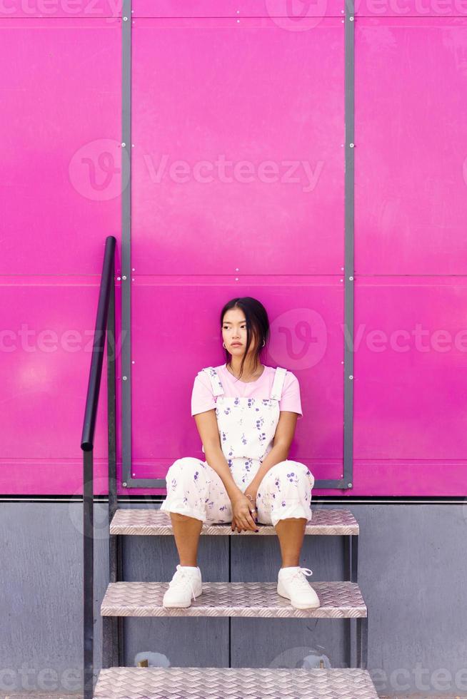 Calm Asian female near pink wall photo