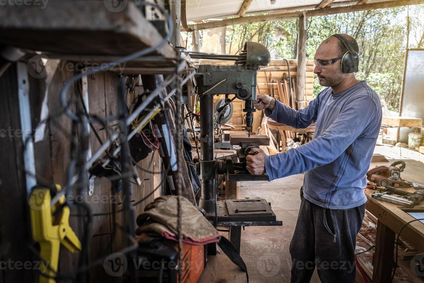 Carpenter drills a hole using a drilling machine. photo