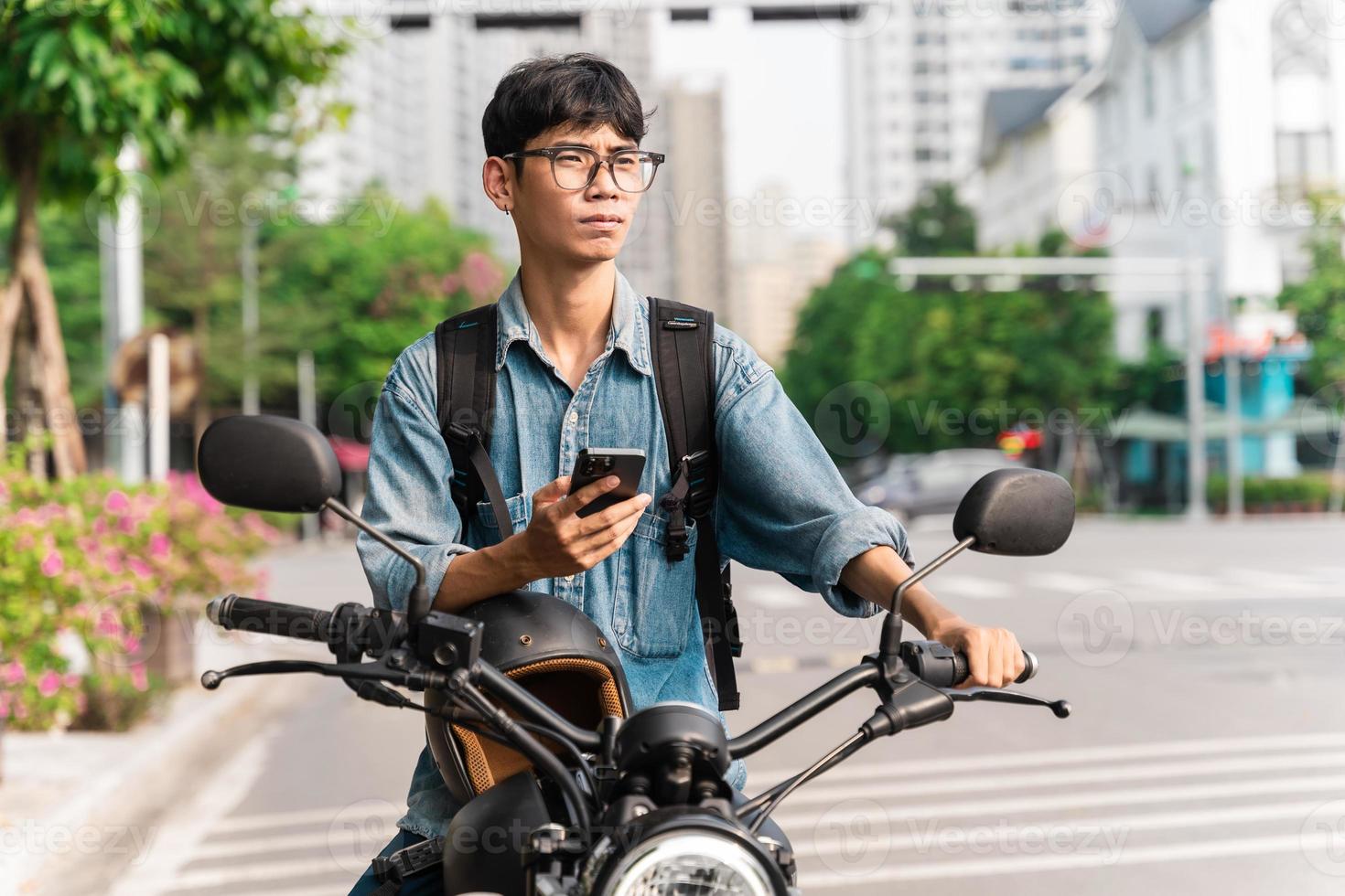 image of asian man, sitting on moto using mobile phone photo