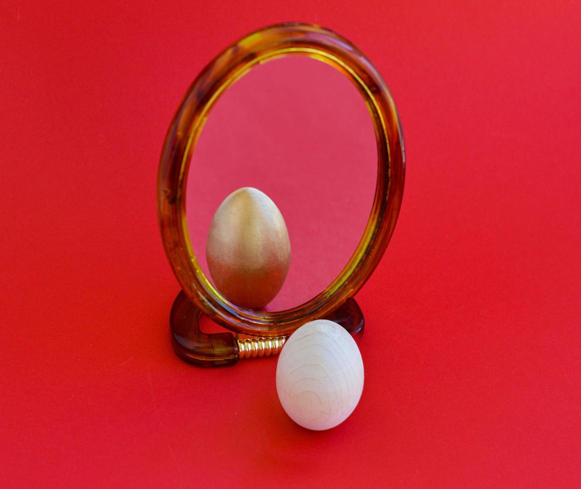 The Easter wooden egg sees its golden reflection in the mirror. Decorated Easter eggs, traditional for Eastern Europe culture. photo