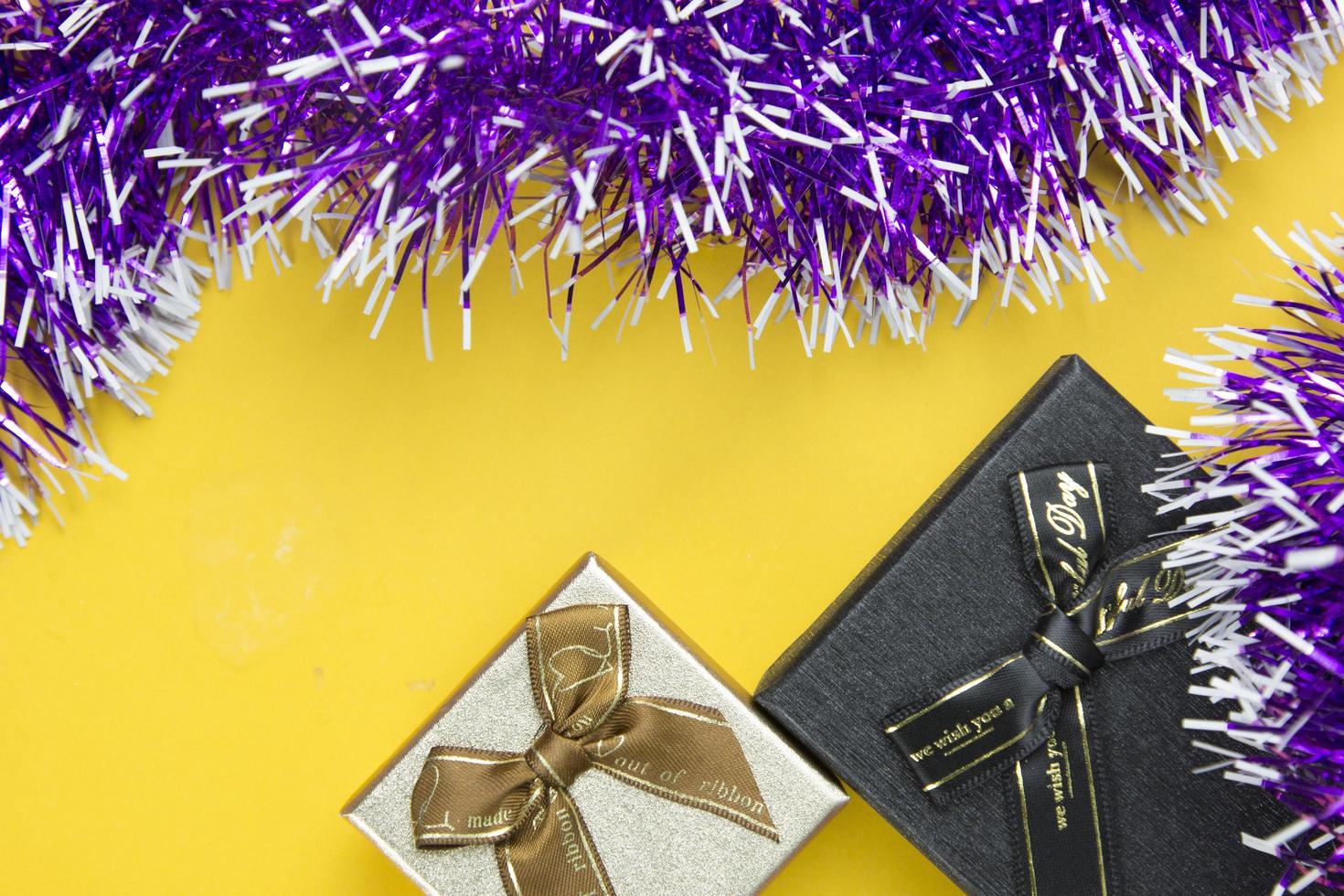 dos cajas de regalo y cintas moradas objeto festivo decorativo colocado sobre fondo amarillo, bonito diseño de conceptos de objetos decorativos de año nuevo. foto