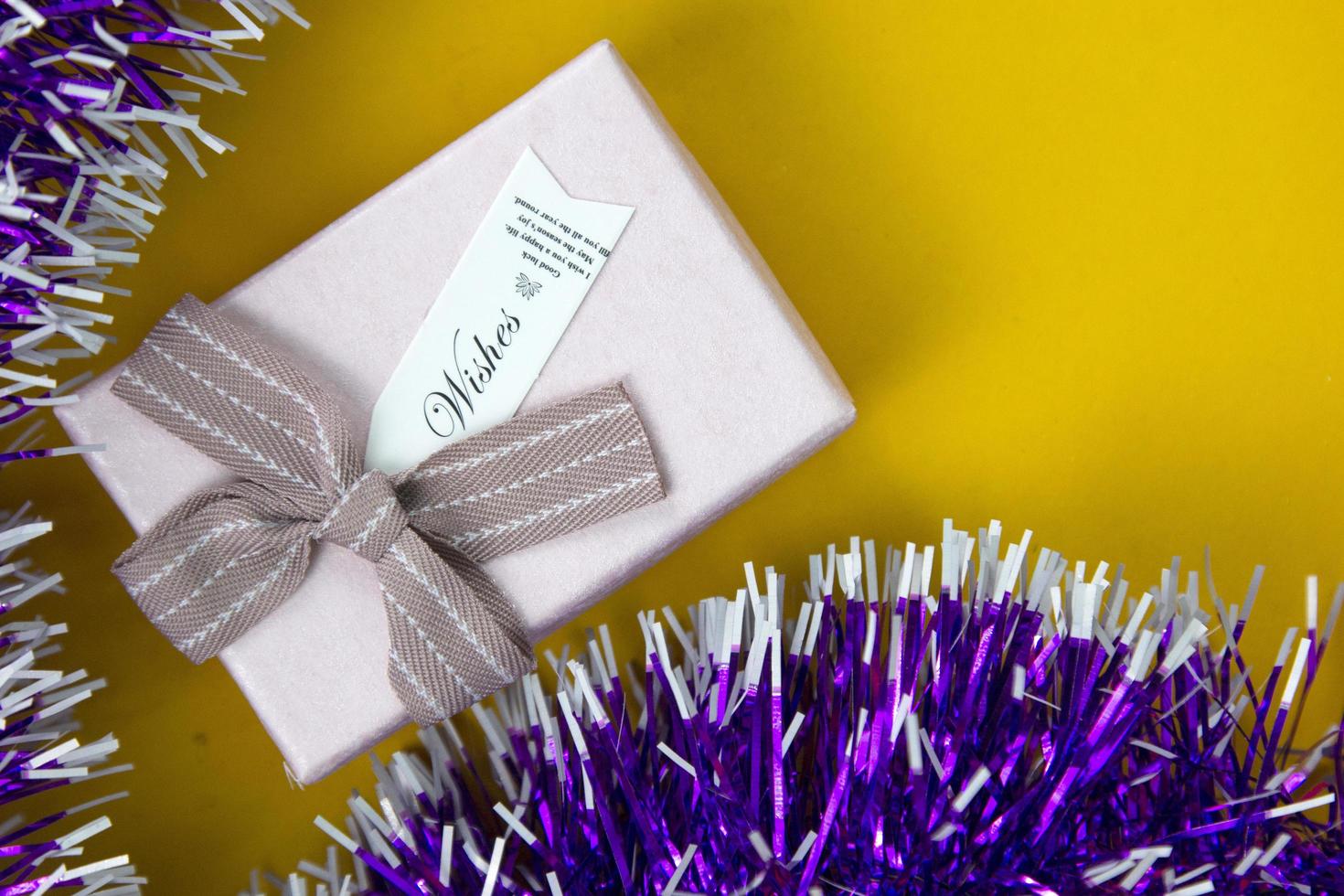 hermosa caja de regalo rosa aislada en amarillo. una caja de regalo con cinta de color brillante y lazo. utilizado en concepto de celebración, navidad y año nuevo. foto