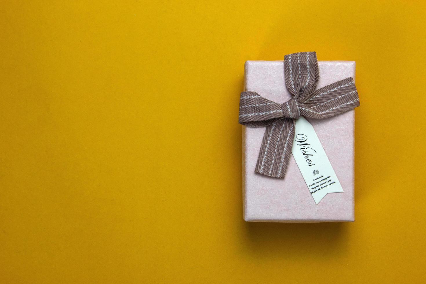 A celebration present and Gift box isolated on yellow. a gift box with bright color ribbon. photo