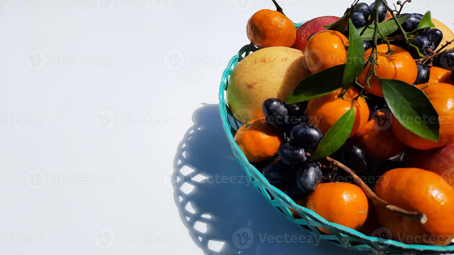Tropical fruit in a green basket on the right on a white background 01 photo