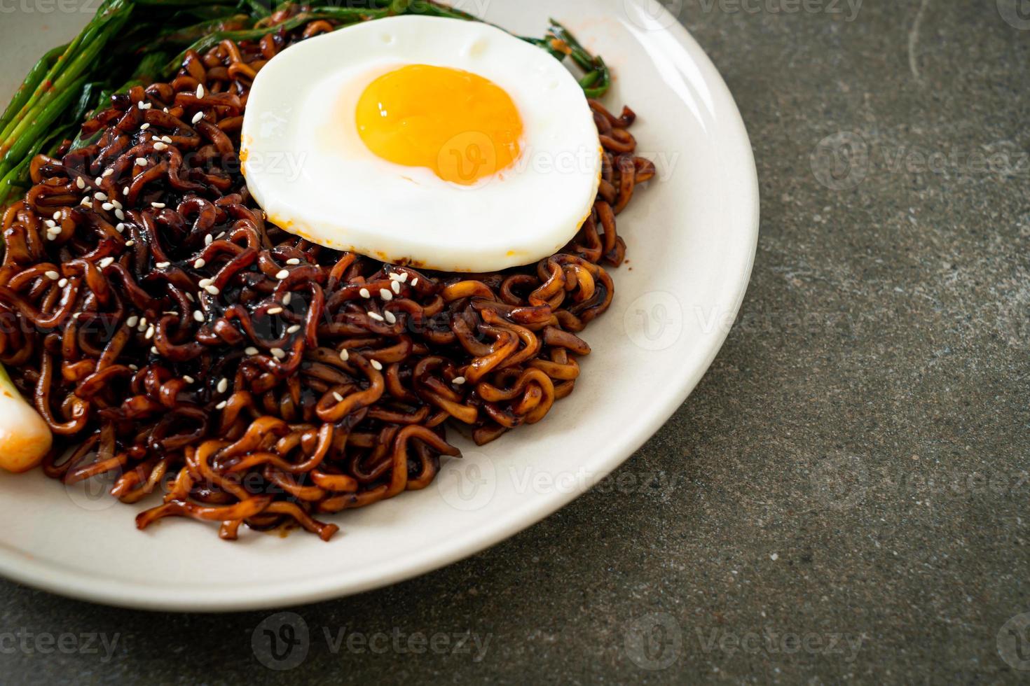 dried Korean spicy black sauce instant noodles with fried egg and kimchi photo
