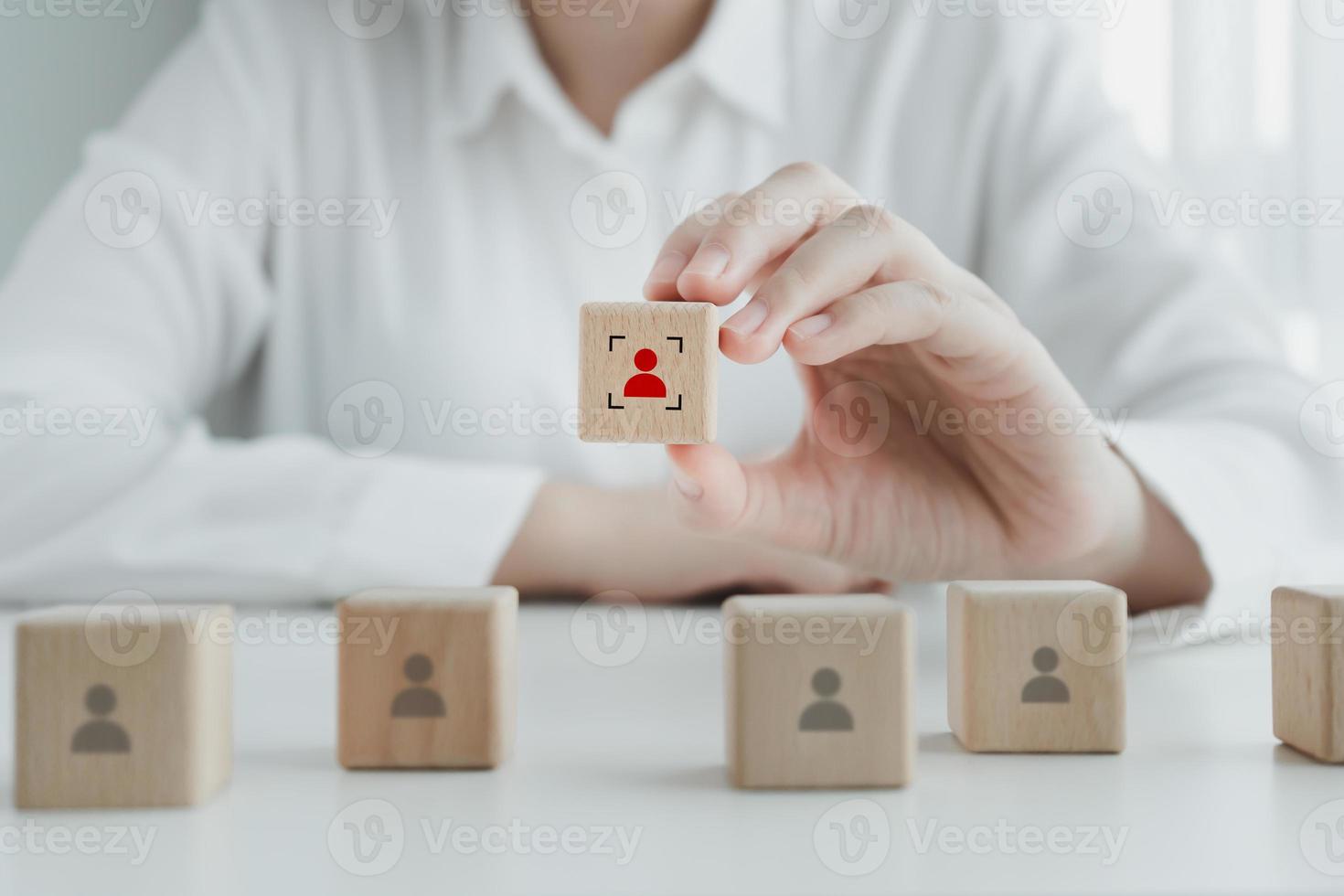 Hand choosing human icon on wooden block with focus frame. Business hiring and recruitment selection. Career opportunity. Human Resource Management. Choice of new employee or leader from the crowd. photo
