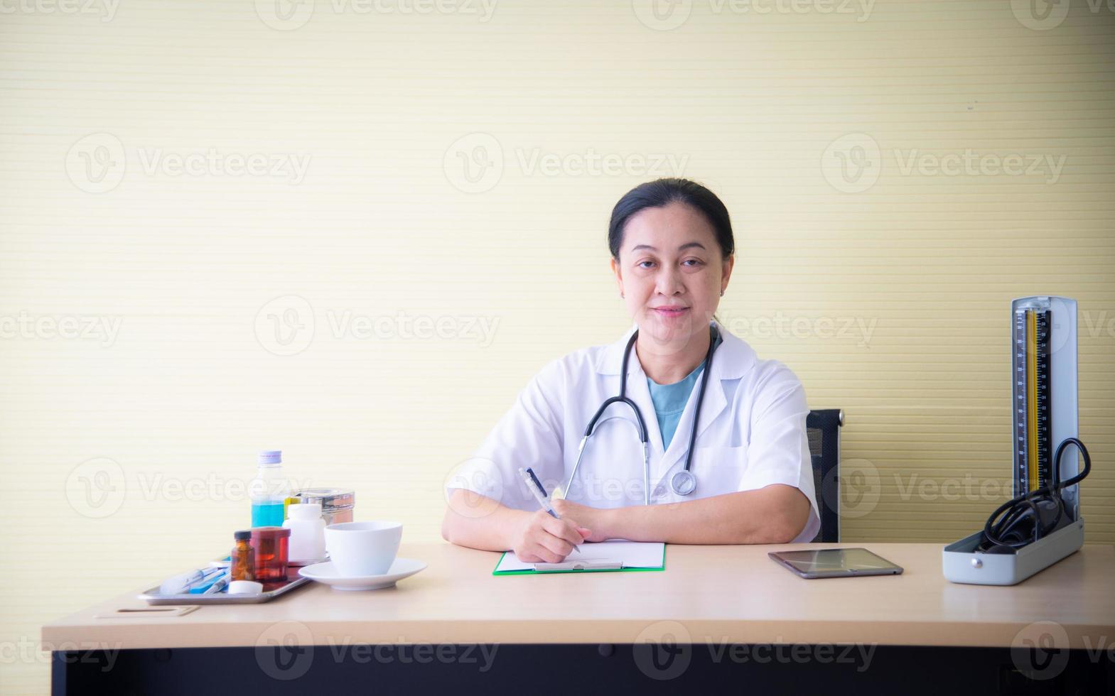 una doctora con dispositivos médicos está revisando la salud del paciente y tomando nota del libro blanco en el hospital, que es el negocio de la salud foto