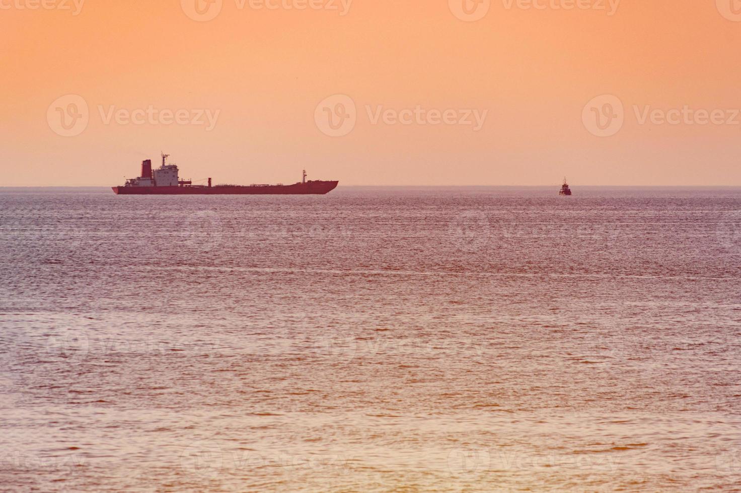 Little tugboat and big cargo ship. Beautiful sunset over sea. Breathtaking travel view, copy space. photo