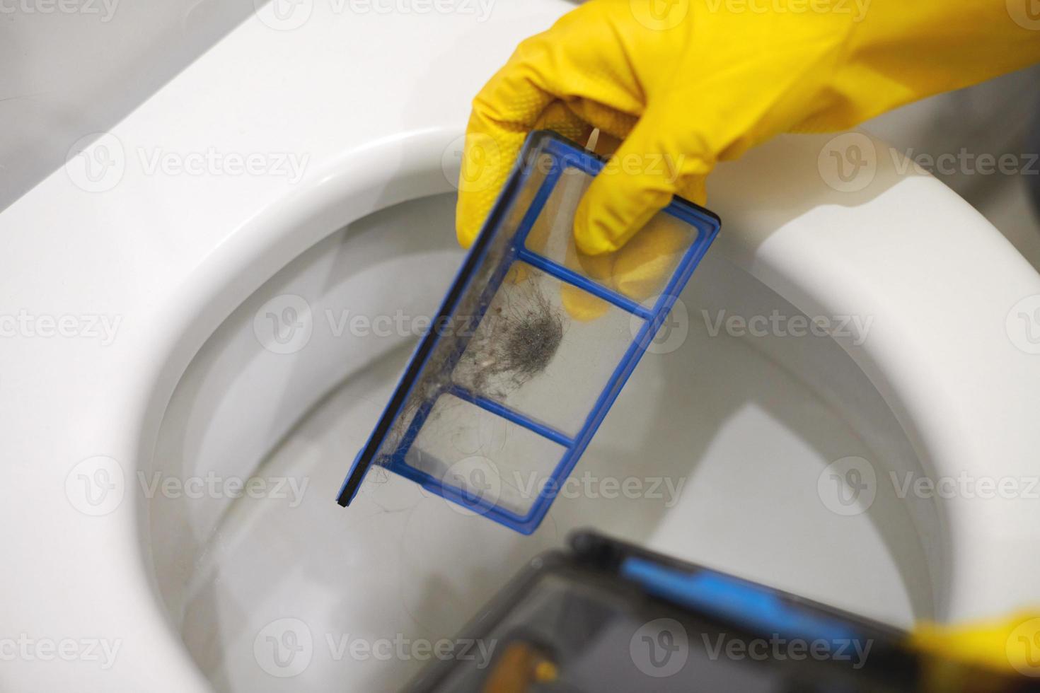 Hands in rubber gloves throw out trash in toilet, close up. photo