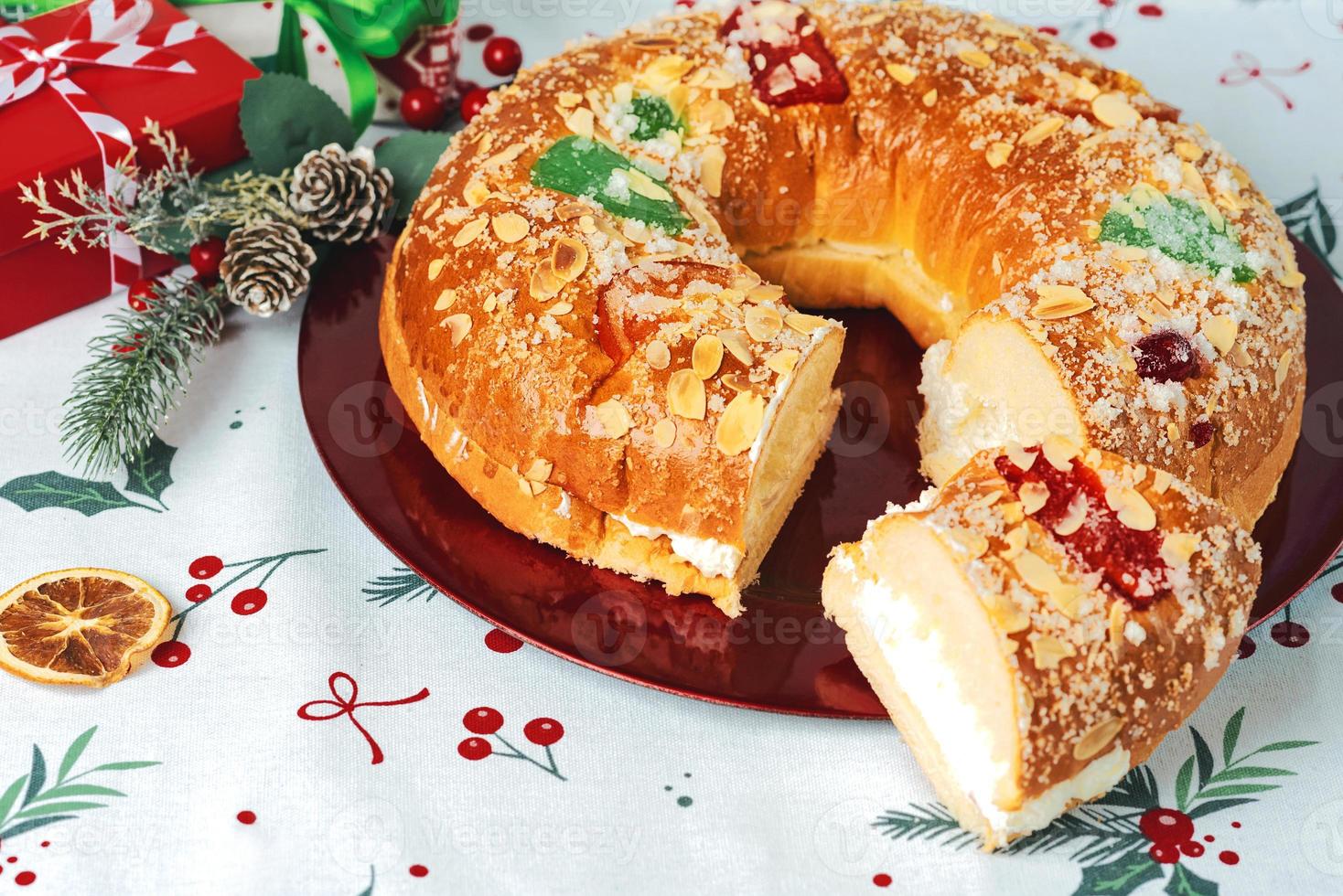 roscon de reyes con crema y adornos navideños en un plato rojo. concepto del día de reyes pastel de reyes magos postre típico español para navidad foto