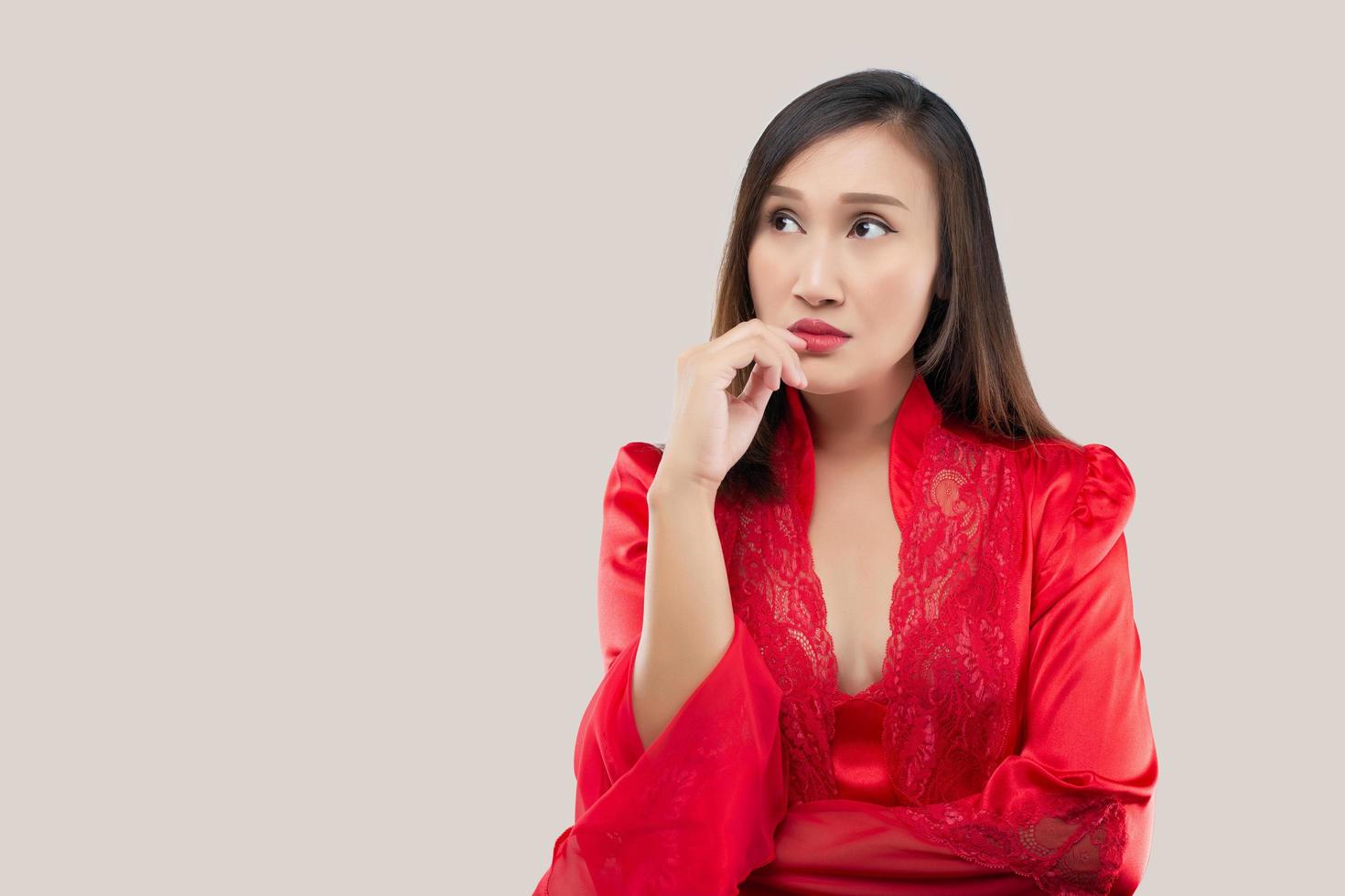 Asian woman in a red satin nightwear thinking photo