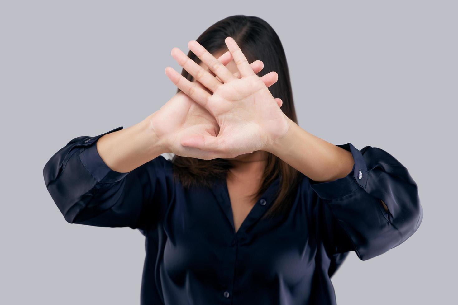 Woman in black suit showing her denial with no on her hand against gray background photo