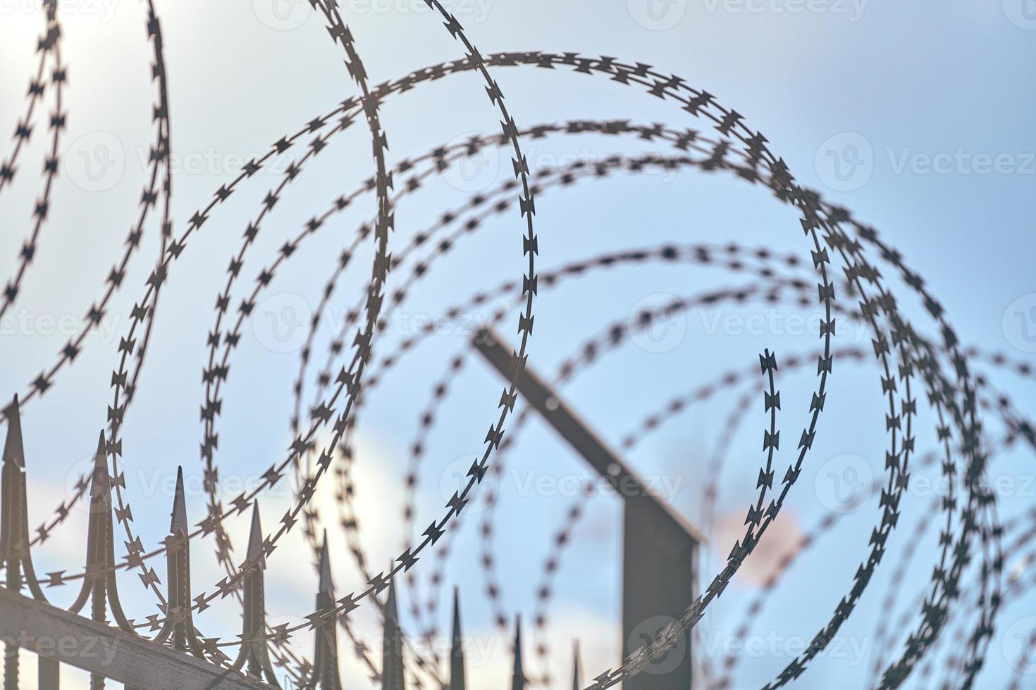 Barbed wire on fence, steel grating fence with barbs photo