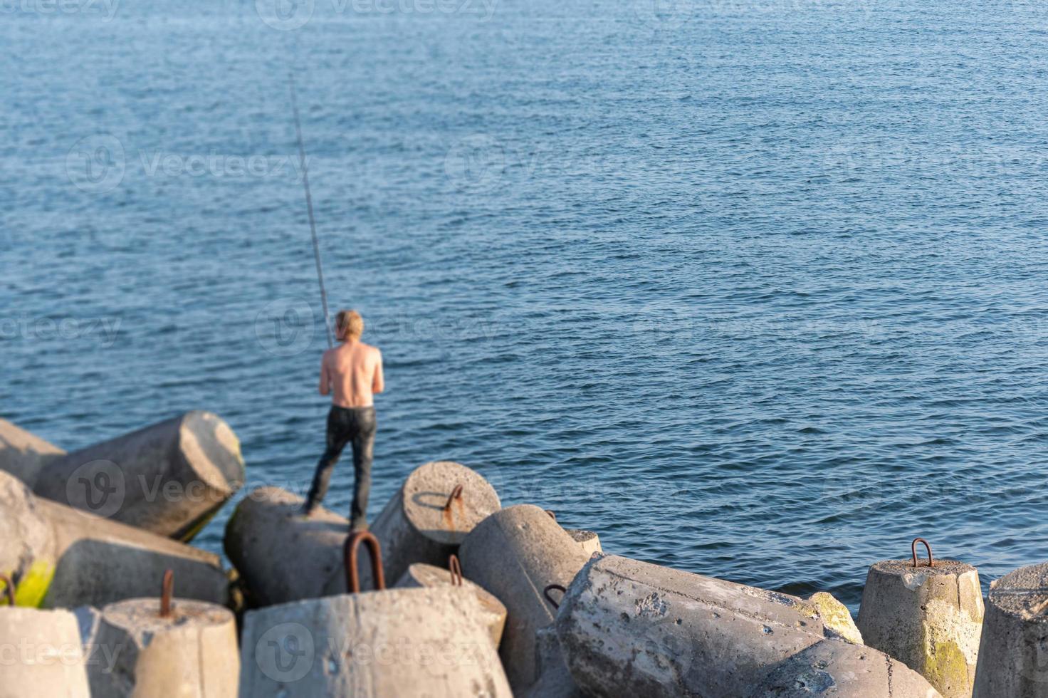 Fisherman fishing from breakwaters, copy space. Bare back pescetarian man  with fishing rod. Rich catch, fish place. 14672367 Stock Photo at Vecteezy