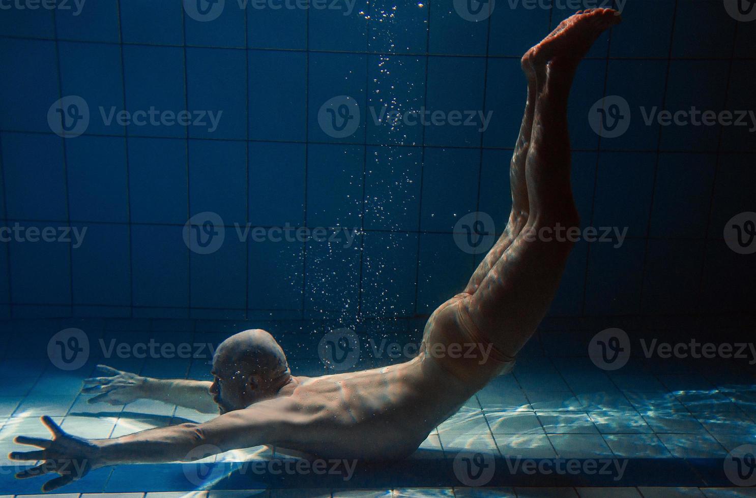 hombre de deporte atlético bajo el agua en la piscina. deportes, yoga, concepto de buceo libre foto