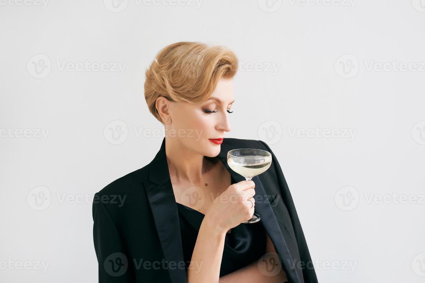 mature stylish elegant woman in tuxedo with glass of sparkling wine. Party, celebration, anti age concept photo
