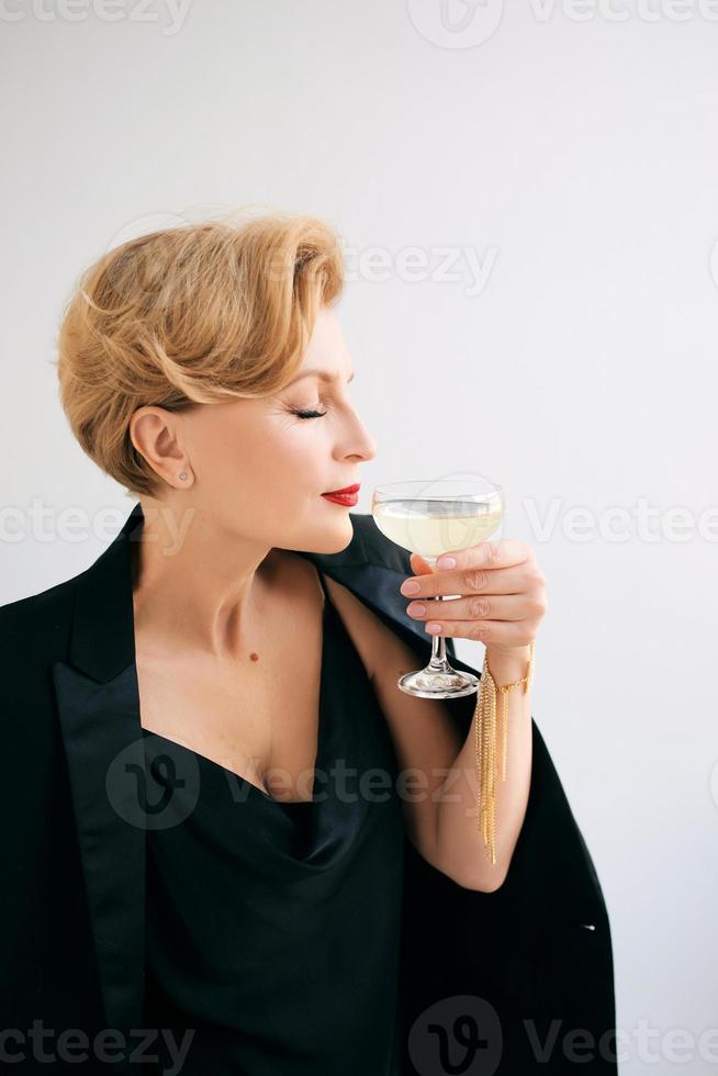 mature stylish elegant woman in tuxedo with glass of sparkling wine. Party, celebration, anti age concept photo