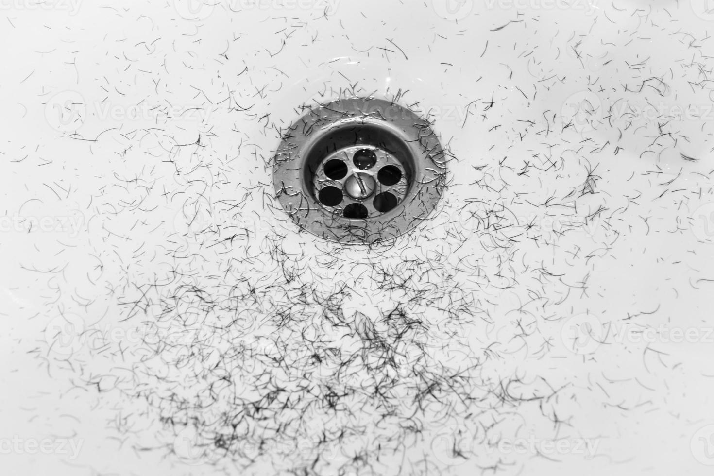 Dirty wash hand basin showing grungy drain with bits of hair photo