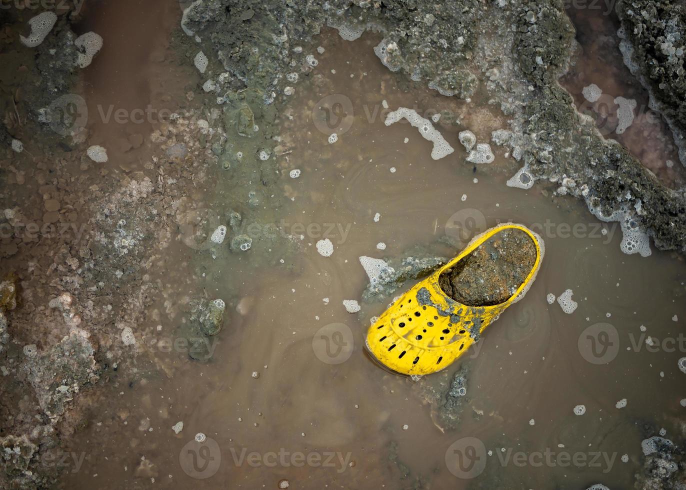 zapato amarillo muy sucio en la orilla de un lago salado en un día soleado. foto