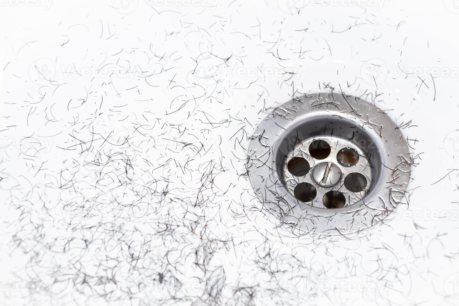 Dirty wash hand basin showing grungy drain with bits of hair photo