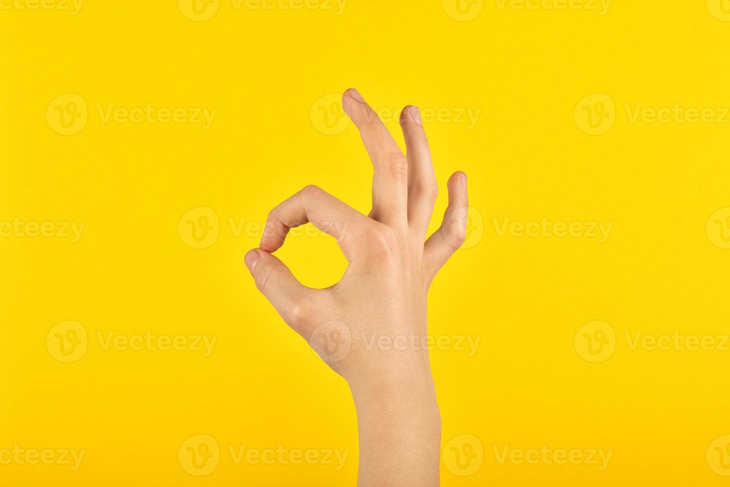 Child's hand showing consent with fingers. Figure on a yellow background. OK. photo