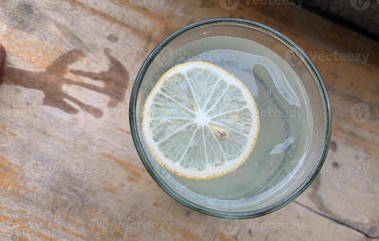 a glass of lemon soda seen from above, served on a wooden table photo