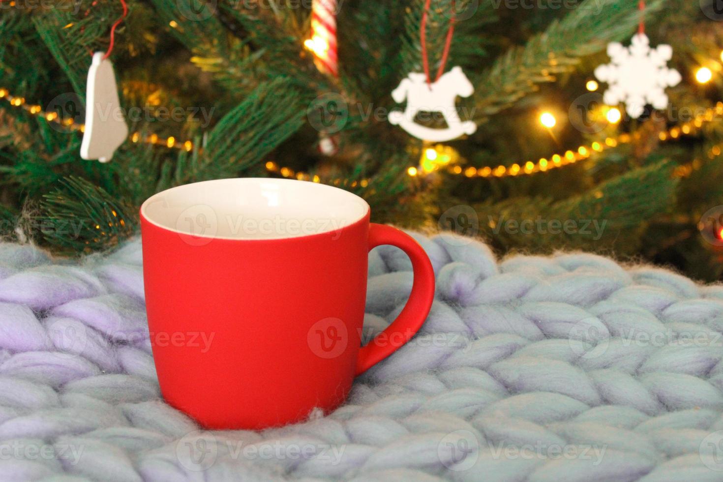 Blank red mug with christmas tree on background,mat tea or coffee cup with christmas and new year decoration,horizontal mock up with ceramic mug for hot drinks,empty gift print template. photo