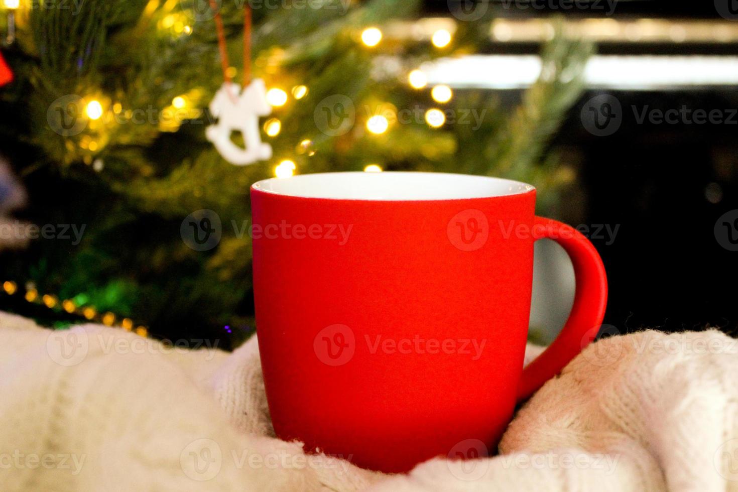 Blank red mug with christmas tree on background,mat tea or coffee cup with christmas and new year decoration,horizontal mock up with ceramic mug for hot drinks,empty gift print template. photo