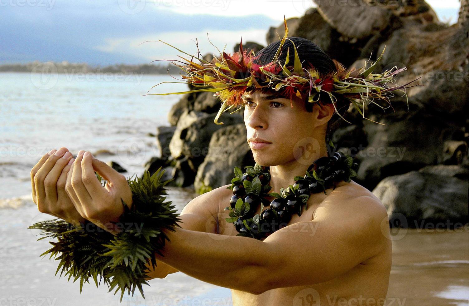 Male Hula Dancer poses on the beach with a giving gesture of the hula dance.. photo
