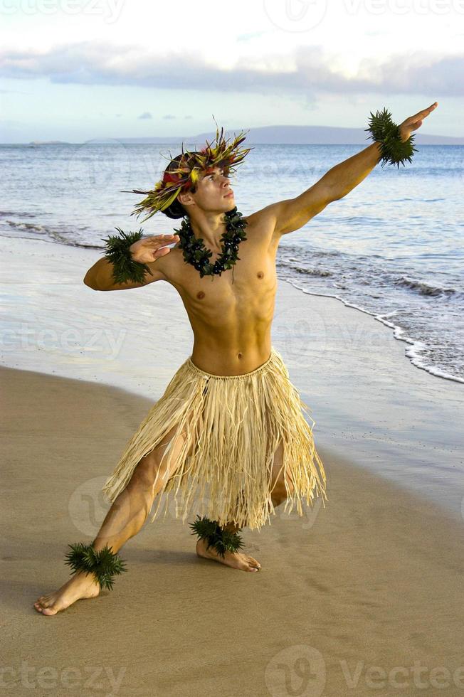 Male Hula Dancer performing on the beach next to the waters edge. photo