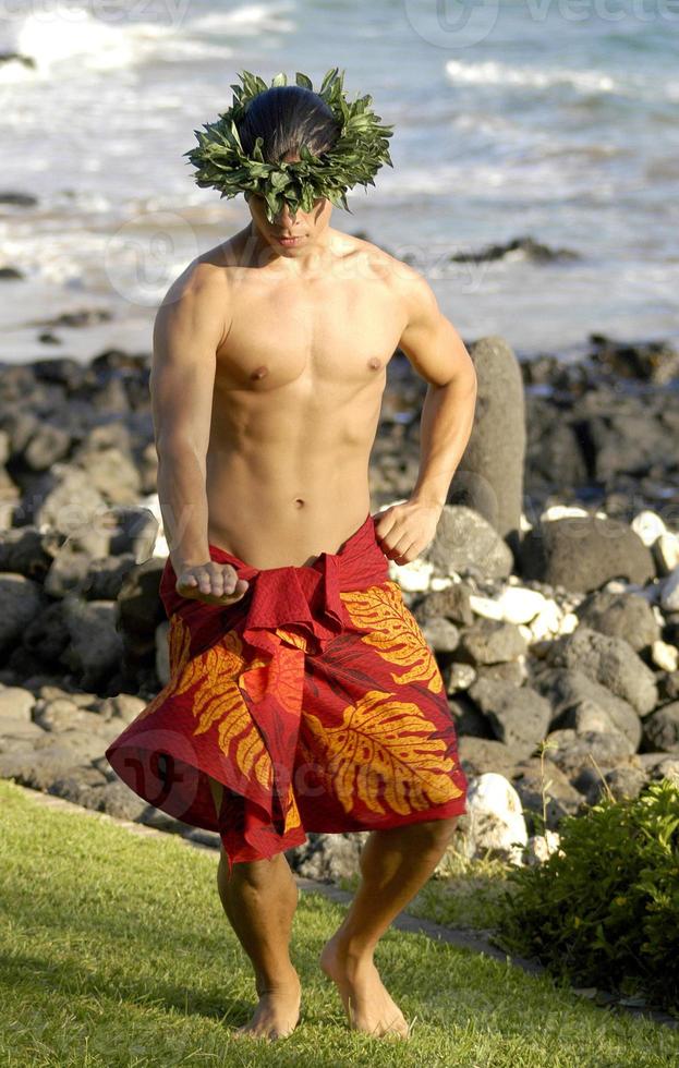 Male hula dancer performs at the shoreline with manly moves and traditional male hula poses. photo