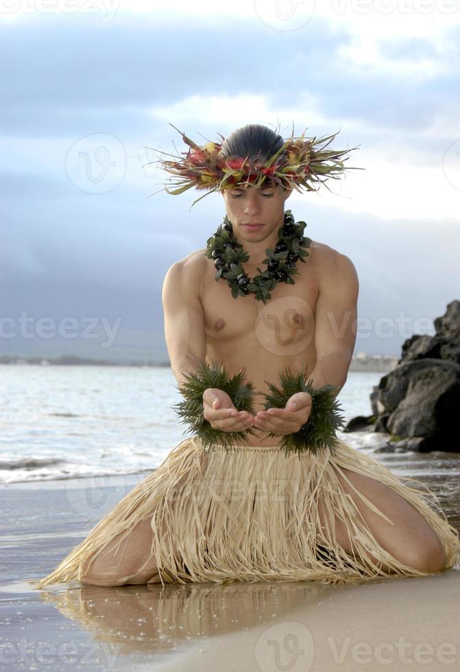 un joven bailarín de hula hace gestos de dar u ofrecer en un baile de hula. foto