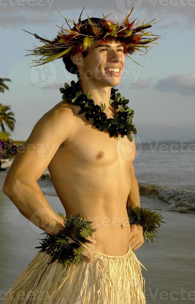 un sonriente bailarín de hula masculino posa en la playa al atardecer. foto