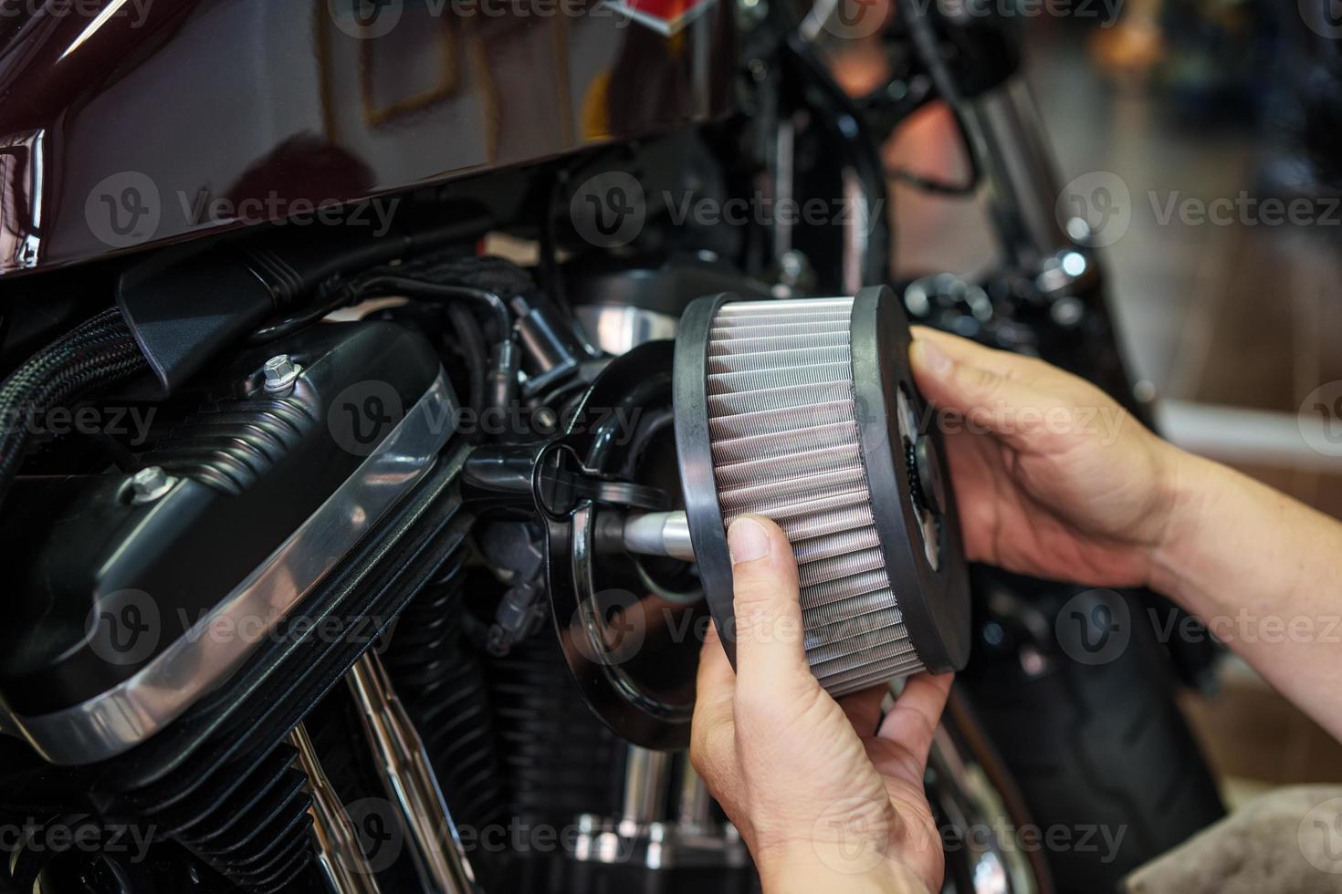 El mecánico revisa el filtro de aire de la motocicleta en el garaje, la placa trasera promueve un flujo de aire suave. mantenimiento de motocicletas, concepto de reparación foto