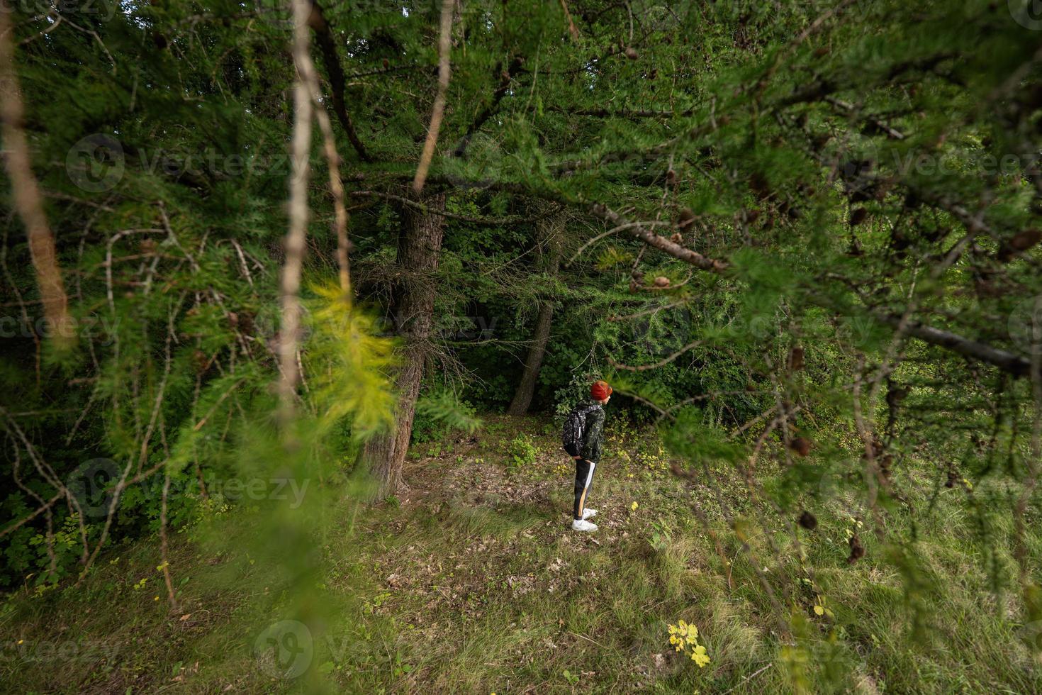 Boy with backpack in wild forest hiking. photo