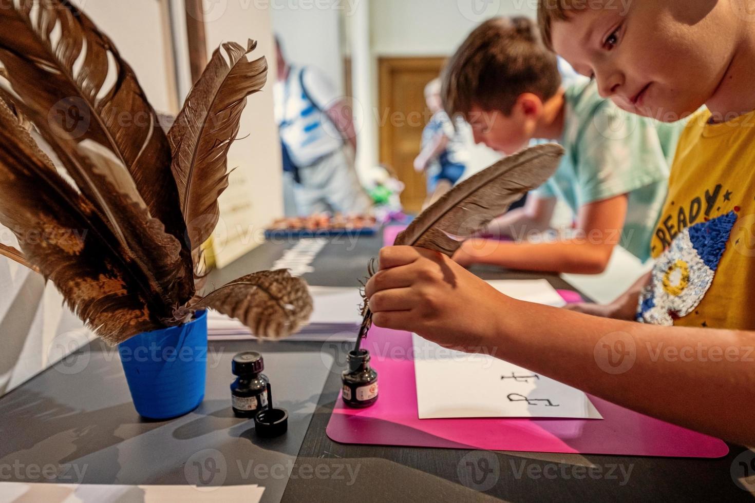 niño escribiendo con pluma de ave en el escritorio. foto