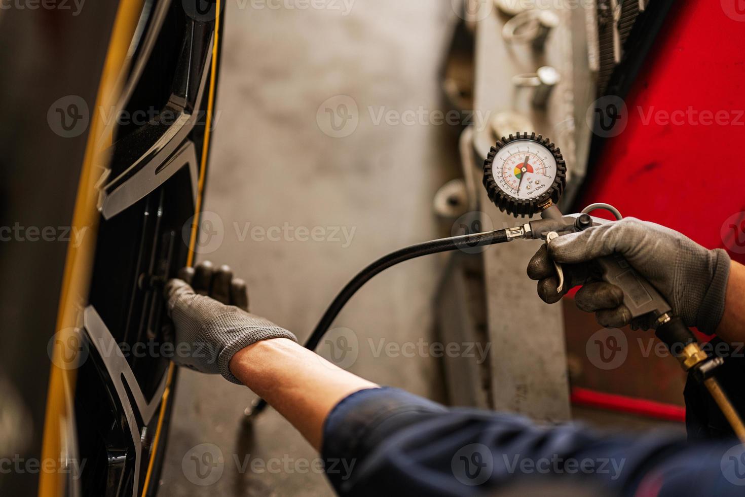 Mechanic checks tire pressure in yellow sport car suv. photo