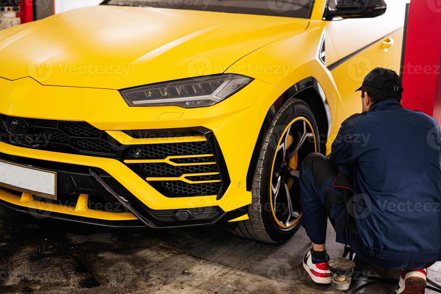 Mechanic checks tire pressure in yellow sport car suv. photo