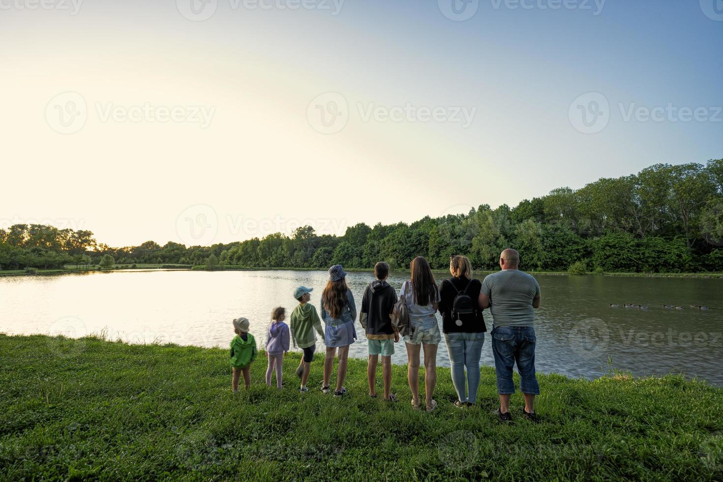 Big and large family against lake in sunrise. Six children. Parents and kids. photo