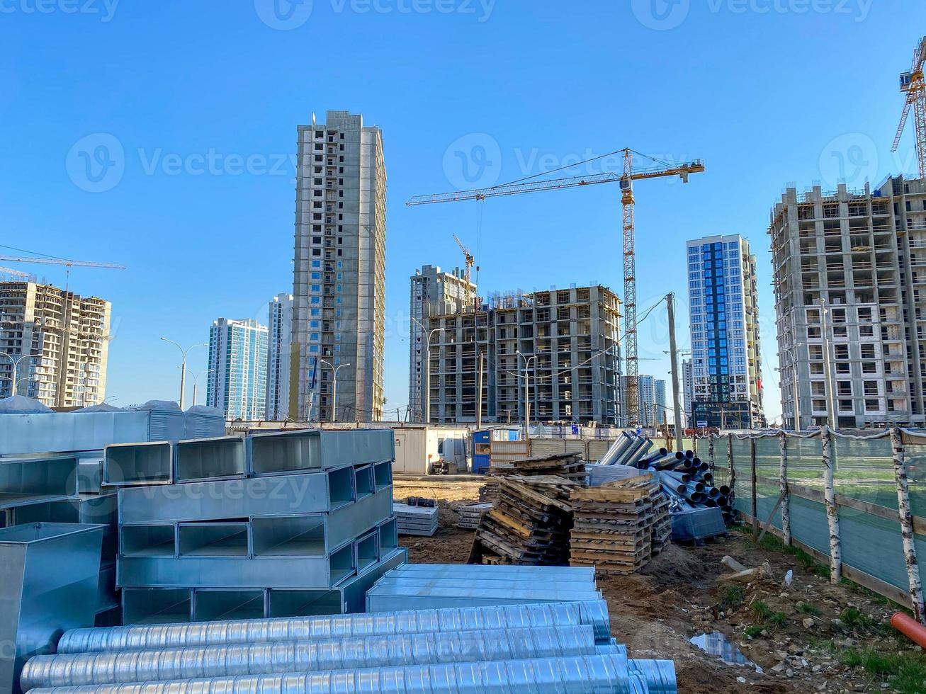 Laying concrete sewer wells and sewer pipes. Sewage drainage system for a multi-story buildings. Tower cranes in action at a construction site. Building the homes photo