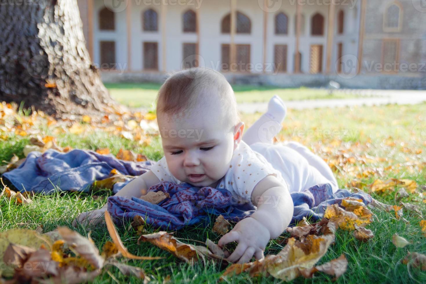 una niña linda está jugando con hojas amarillas secas en un parque por primera vez en su vida. foto