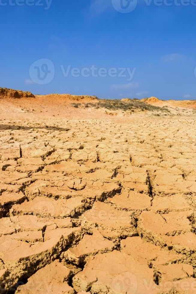 Landscape with dry cracked soil and blue sky. photo