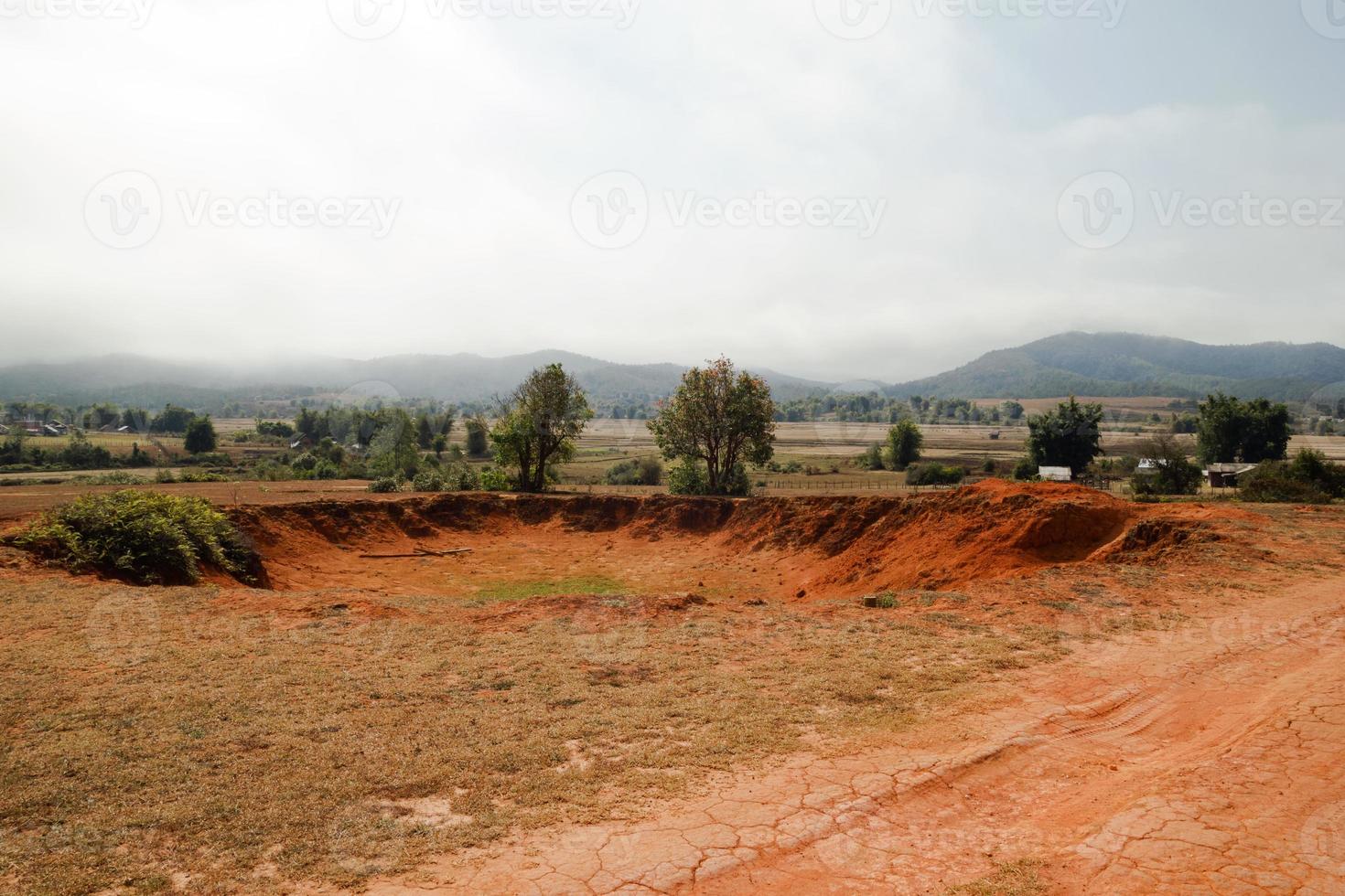 paisaje de campo de cráteres de bomba con pueblo y montañas en el fondo en la provincia de xieng khouang, laos. uno de los lugares más fuertemente bombardeados en Laos. foto