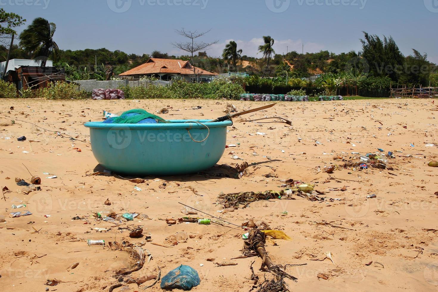 View on a sandy beach near to fishing village with a lot of garbage. Pollution of a coastline. Mui Ne, Vietnam. photo