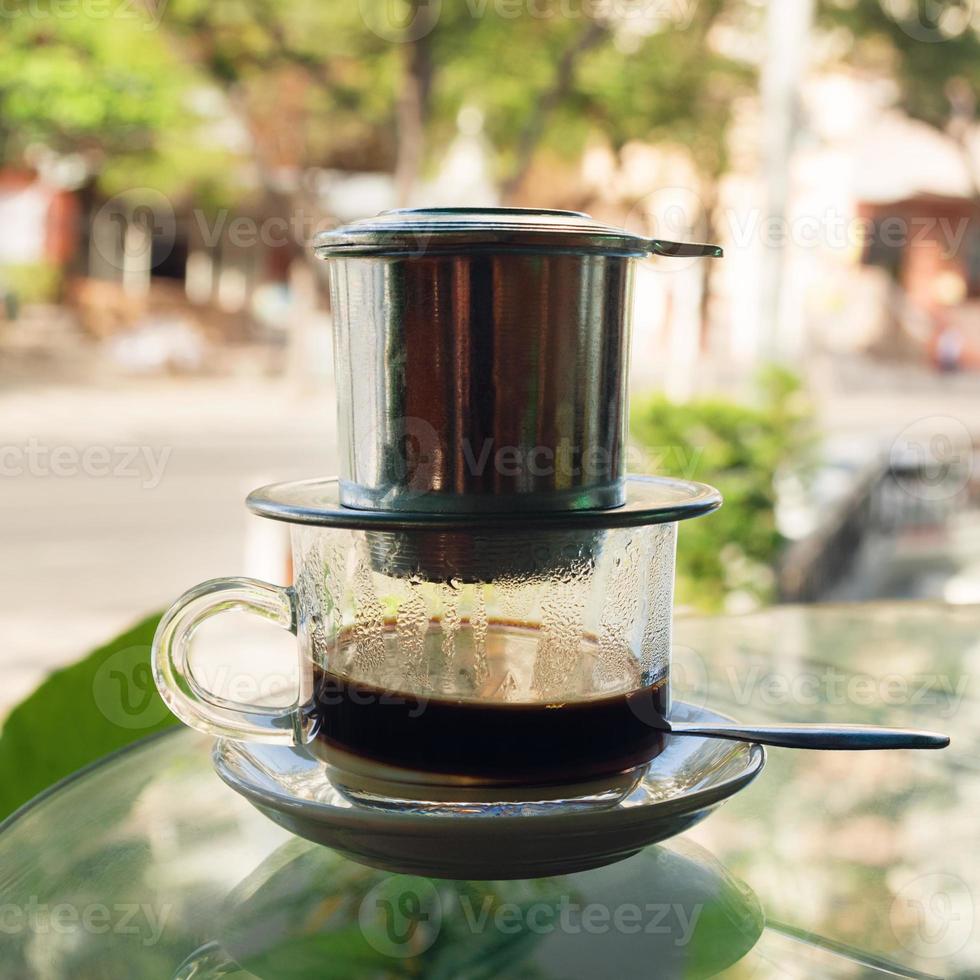 Drip Black Coffee in Vietnamese style with condensed milk on a glass table. Traditional method of making coffee. photo