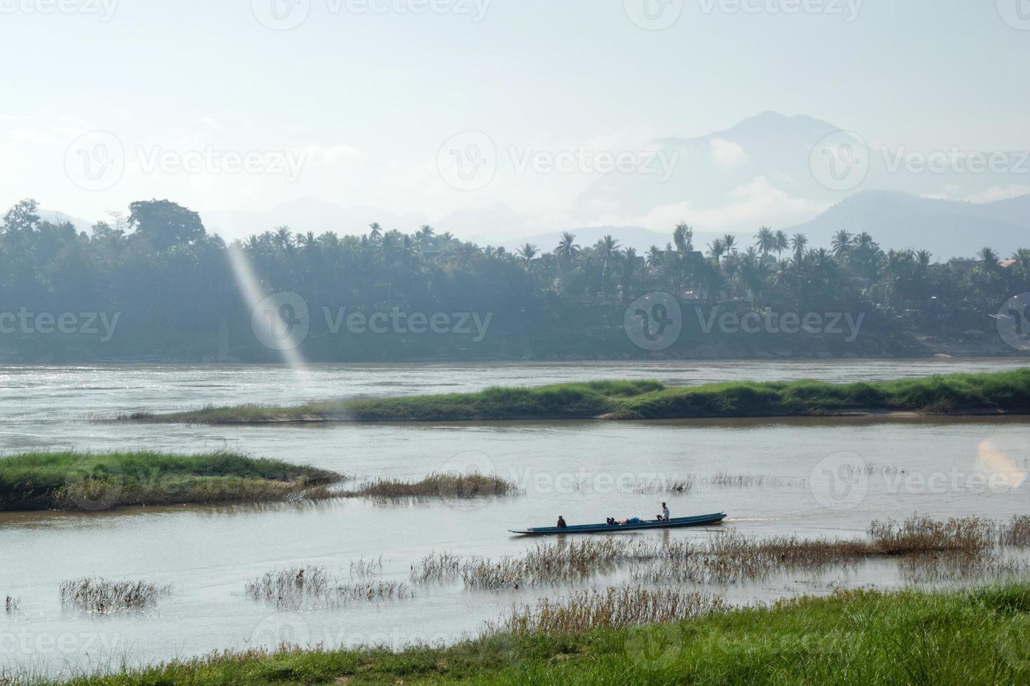 Tropical landscape on Mekong River with boat, palm trees and mountains on the bank in sunlight. Luang Prabang, Laos. photo