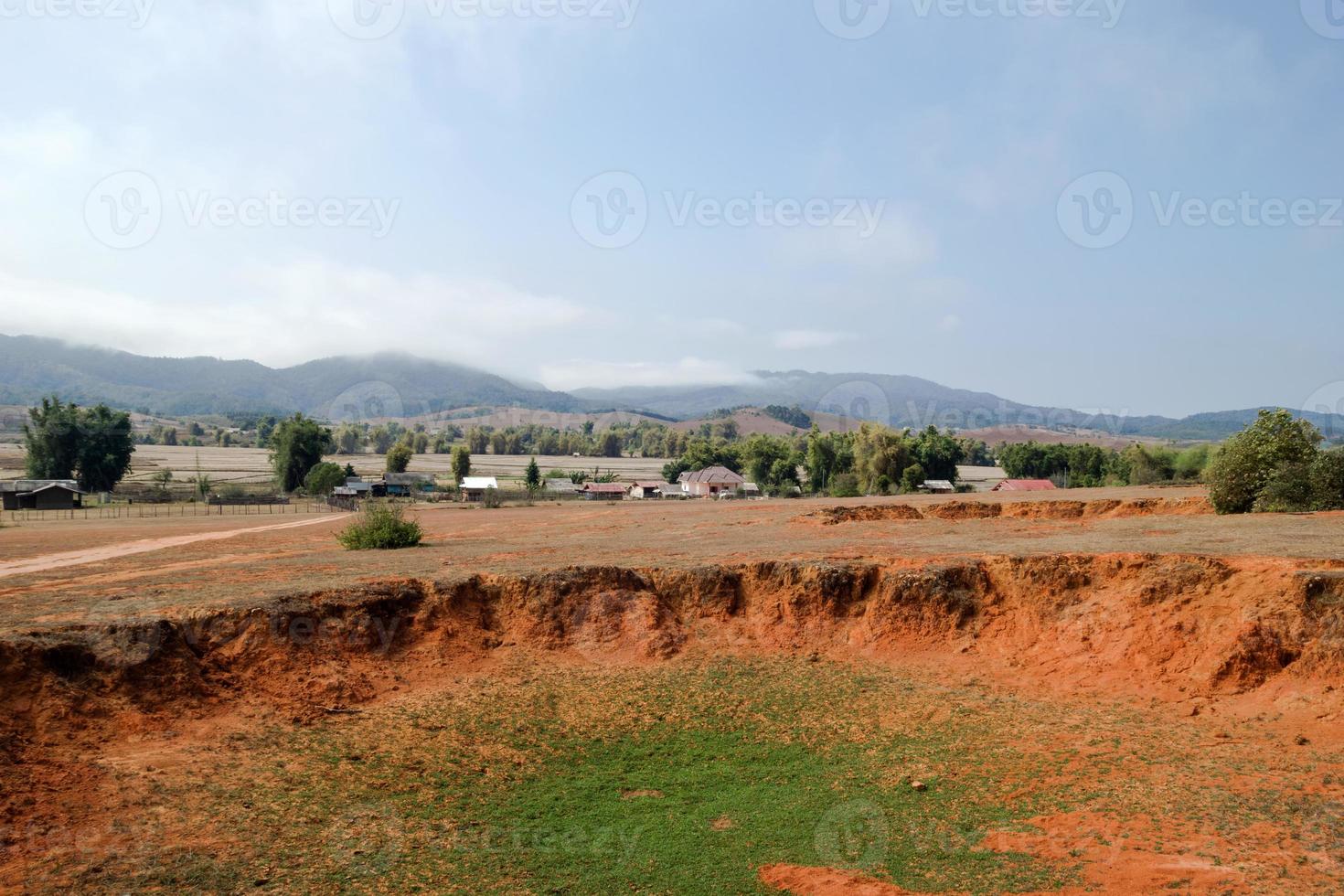 Landscape of Bomb craters field with village and mountains on background in Xieng Khouang Province, Laos. One of the most heavily bombed place in Laos. photo