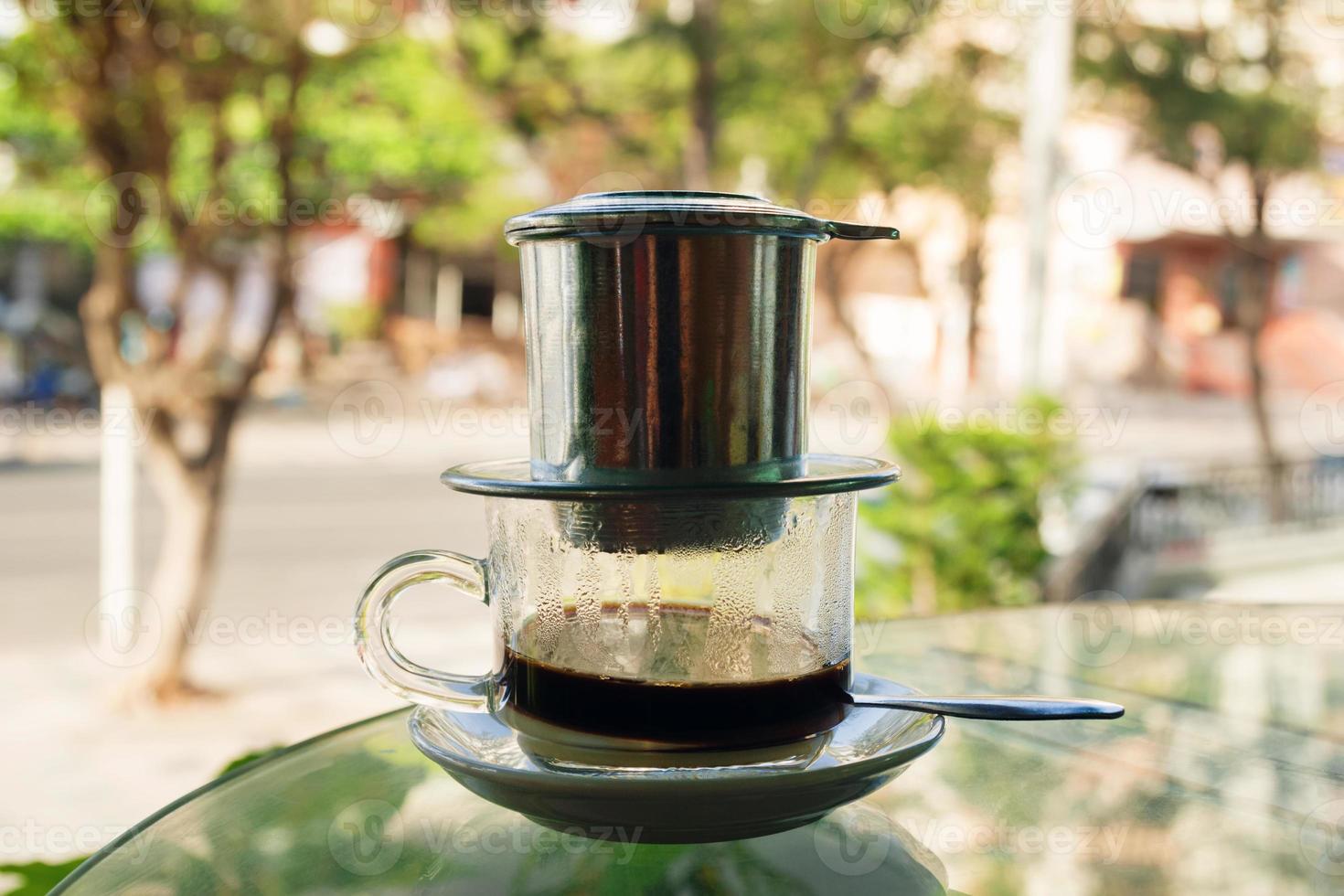 Drip Black Coffee in Vietnamese style with condensed milk on a glass table. Traditional method of making coffee. photo